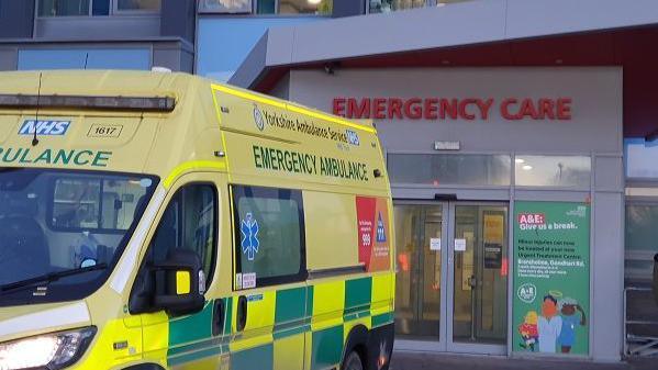 An ambulance is waiting at a bay beside the emergency department doors.