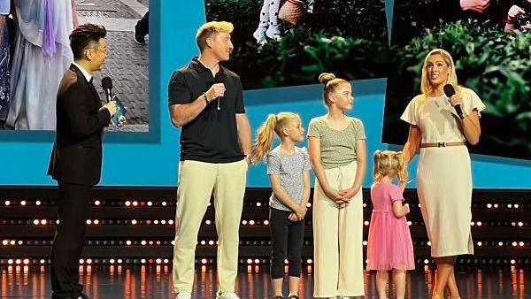 The family on a stage with microphones being interviewed by a host