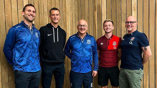 Five men, who include the programme founders and some of the programme team, standing together smiling at the camera