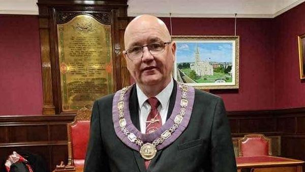 William Walker dressed in a suit and wearing a chain and floret.