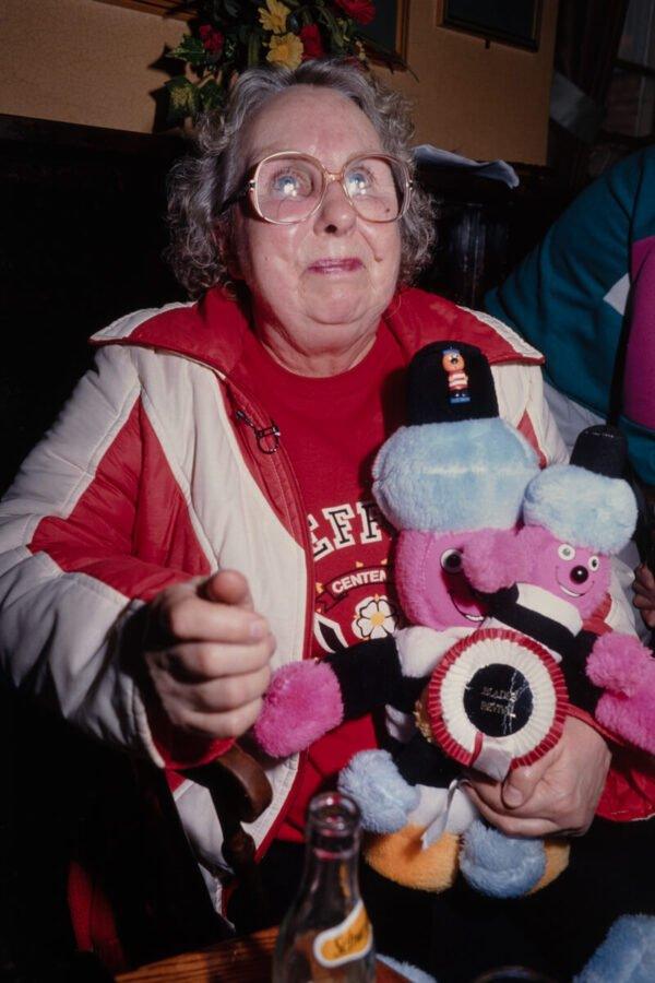 A woman holding a Bertie Bassett doll