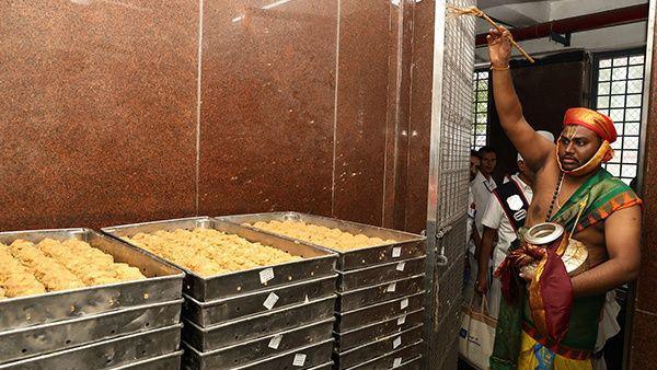 A Tirupati priest sprinkles holy water on trays of laddu at their kitchen as part of a purification ritual