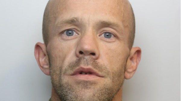 Mugshot of Daniel O'Sullivan. He is bald and has stubble on his chin. He has blue eyes. He is pictured against a plain white background, looking directly at the camera. His mouth is open slightly. 