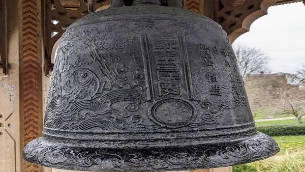 A bell ornately cast in a dark metal  