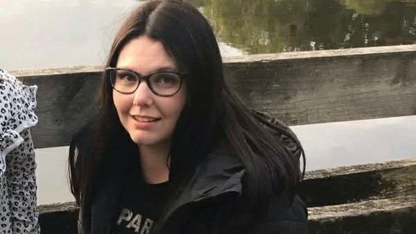 Chloé Blick crouching next to a lake at a nature reserve.