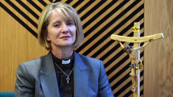 Bishop of Warrington Bev Mason in front of wooden wall with black stripes on it 