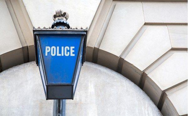 A close-up of a blue lamp on a building with the word "police" on it.