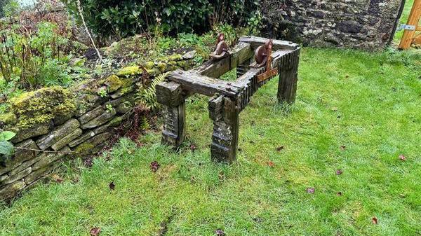 The old wooden oak frame pictured since its centrepiece large sandstone wheel was stolen. Markings in the grass in the foreground show where the heavy wheel was dragged away.  