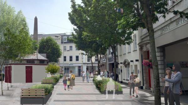 The image shows a projection of a pedestrian-friendly urban street scene. People are walking along a tree-lined street with benches. An obelisk-like structure stands in the background.