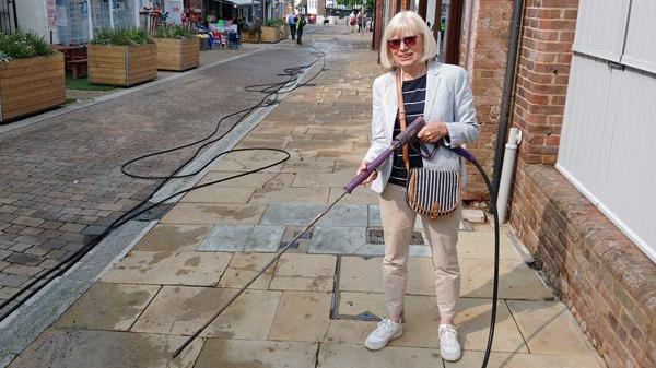 Rosemary Hobbs of Mole Valley District Council demonstrates the jet washing equipment used to clean gum from pavements.