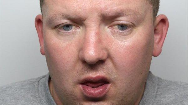 A mugshot of Lee Hodson, wearing a grey t-shirt.