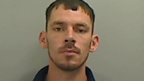 Mugshot of Christopher Sharp. He has short black hair, brown eyes and has a moustache and stubble.