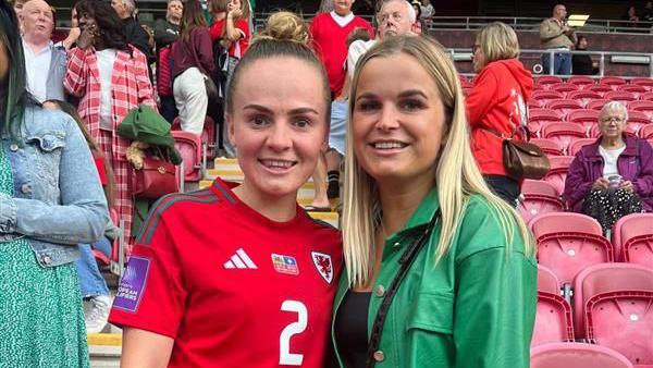 Lily Woodham stands in a Wales football shirt with her friend at a game