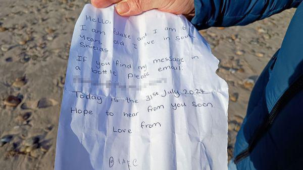 Blake's handwritten message being displayed by finder Jan Cassøe. It reads: Hello, I am Blake and I am six years old. I live in South Shields. If you find my message in a bottle please email me. Today is the 31 July 2024. Hope to hear from you soon. Love from Blake.