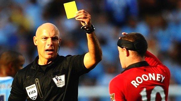 Referee Howards Webb brandishes a yellow card to Wayne Rooney