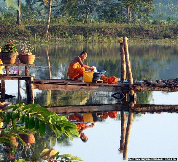 A monk washing his clothes early one morning near a temple in Thailand