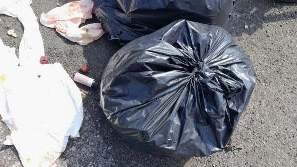 Black bags left in a layby in Salisbury. Rubbish is strewn across the floor.