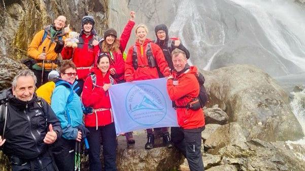 A group of nine people including Sara Crosland on a previous mountain challenge, standing on a mountain