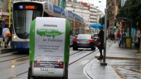 A taxi bike in Geneva bears a poster saying "Save the Minorities in Pakistan"