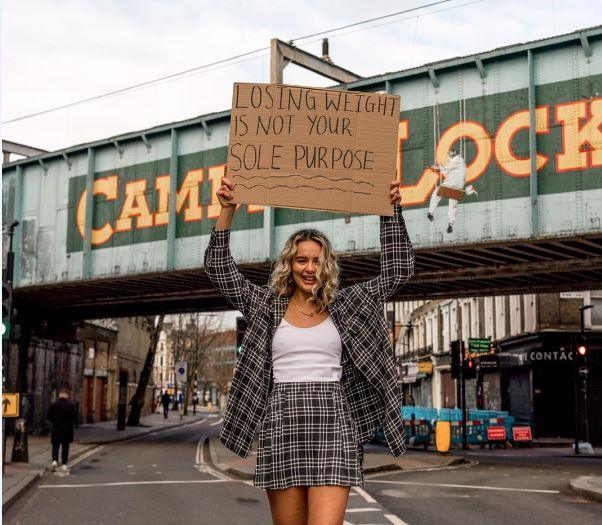 Lauren black holding a sign which says losing weight is not your sole purpose