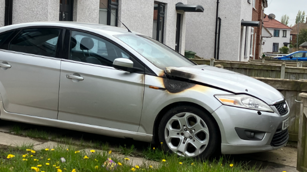 Silver car with damage to the bonnet area parked on a drive