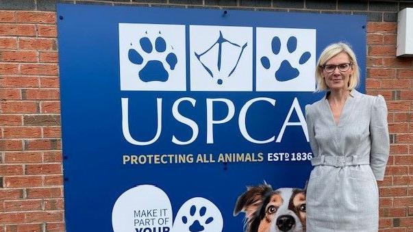 Woman in grey dress beside USPCA sign