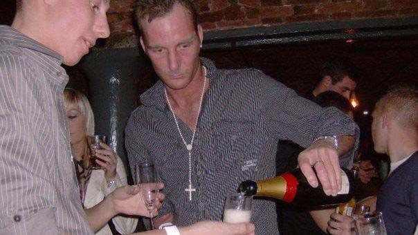 Adam Minett, in a photo taken in the mid-2000s, pours champagne out of a bottle while on a night out in a Liverpool nightclub