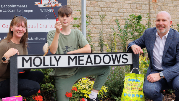 Image shows Fiona, Will and Chris Parker with the new Molly Meadows sign, with some cat treats at the base of the sign. 