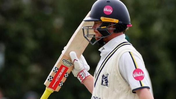 Alex Davies raises his bat after reaching a half-century for the sixth time this season