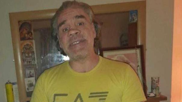 A man in a yellow t-shirt with grey hair.