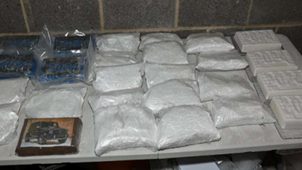 A table displaying multiple sealed plastic bags and rectangular blocks containing a white powdery substance. The items are arranged in neat rows.
