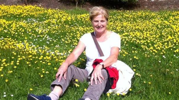 Danielle Carr-Gomm sitting in a grassy field with daffodils, smiling at the camera