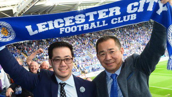 Khun Aiyawatt 'Top' Srivaddhanaprabha with Khun Vichai holding a Leicester City scarf above their heads