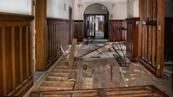 Inside a hallway within County Hall. Floor boards have been torn up with panels of wood lying scattered around.