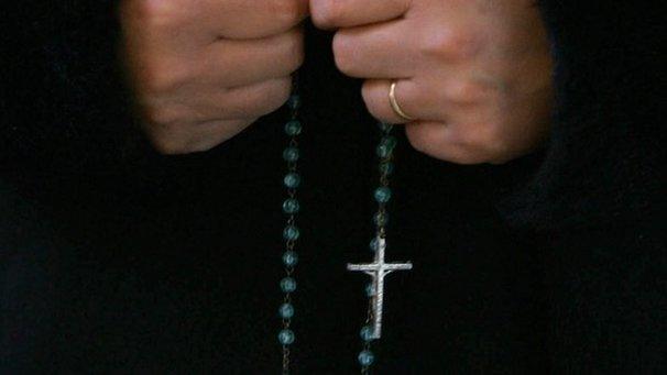 A woman clutches rosary beads (file image)