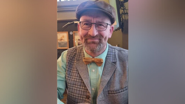 Dave Chester smiling for the camera in what looks like a pub. He is wearing a flat cap and glasses.