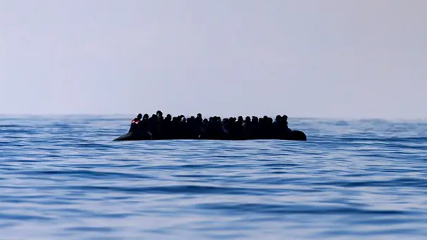 A small boat crowded with people floats in the sea