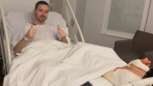 Midfielder Jack Grealish posing in a hospital bed with a bandaged foot