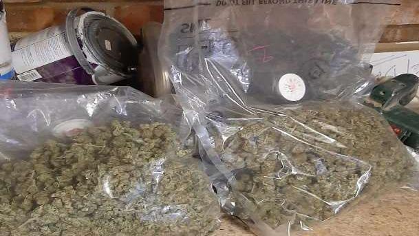 Cannabis is wrapped in plastic bags on top of a work surface.