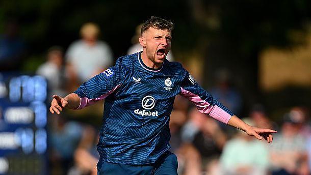Luke Hollman celebrates the wicket of Warwickshire's Taz Ali in the match at Rugby