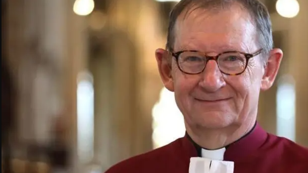 Dean wearing his red cloak with a white tie- smiling for camera 