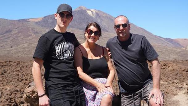 A family holiday photo showing a young man, a woman and an adult male.