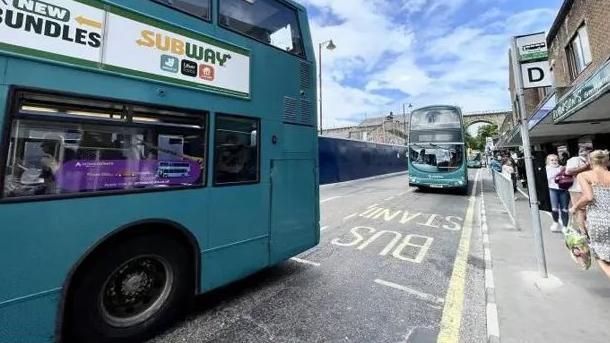 Two buses driving down a street