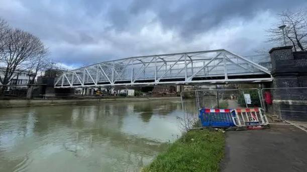 A view of the bridge on an overcast day. There are some barriers on the towpath.