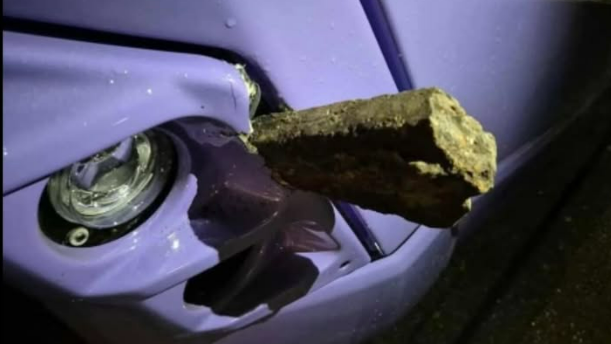 A slab of concrete wedged into the purple bodywork of a bus