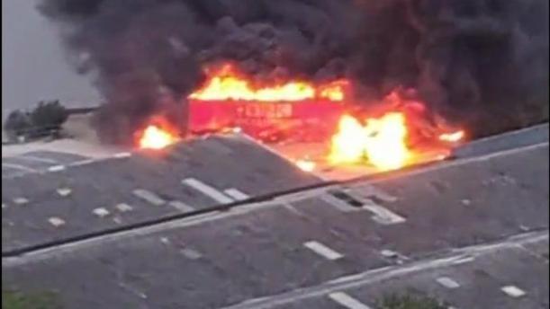 A burning red lorry with the words '鶹Լ World News' is seen in the docklands of east London.