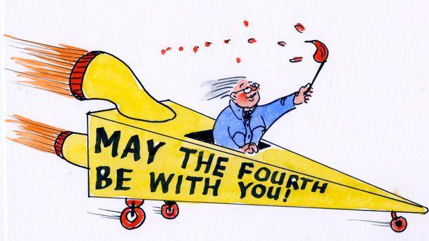 Man in a blue jacket holding a large lit match up in the air while in the front of a triangular-shaped yellow car that has jet engines at the back and May the Fourth be With You! written on the side.