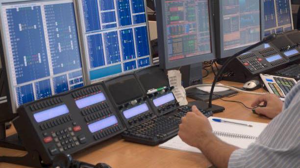 A police control room with a variety of computer screens, consoles, microphones  and keypads 