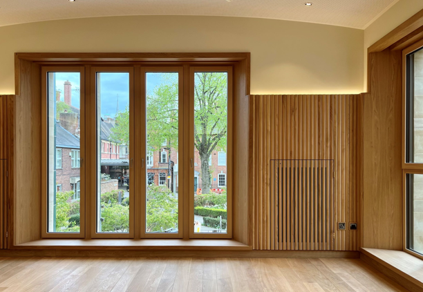 A wood-panelled wall with a large window looking out on to a garden area