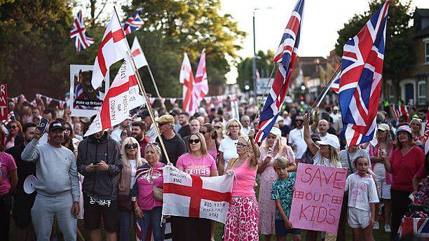 Large crowd of people waving Union Jack and St George flags
